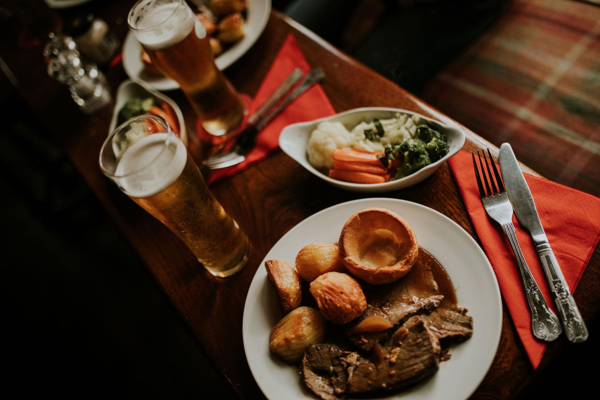 Gedeckter Tisch mit Mittagessen und einem Glas Bier.