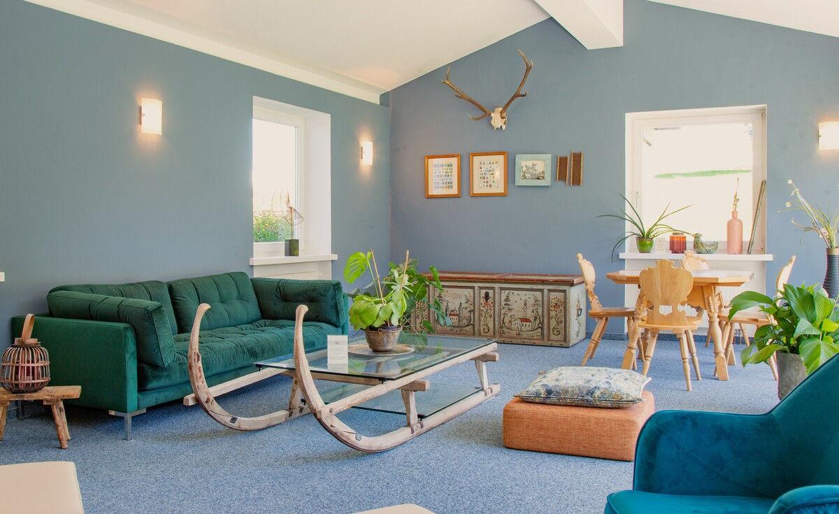 Blaue Lounge mit historischem Hörnerschlitten und Sitzgruppe.