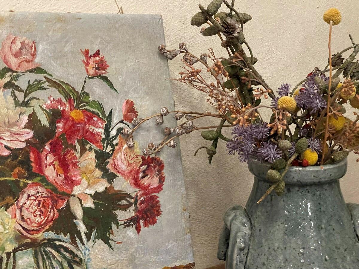 Blumenstillleben an der Wand neben einem Strauß Trockenblumen in Zinkkrügen.