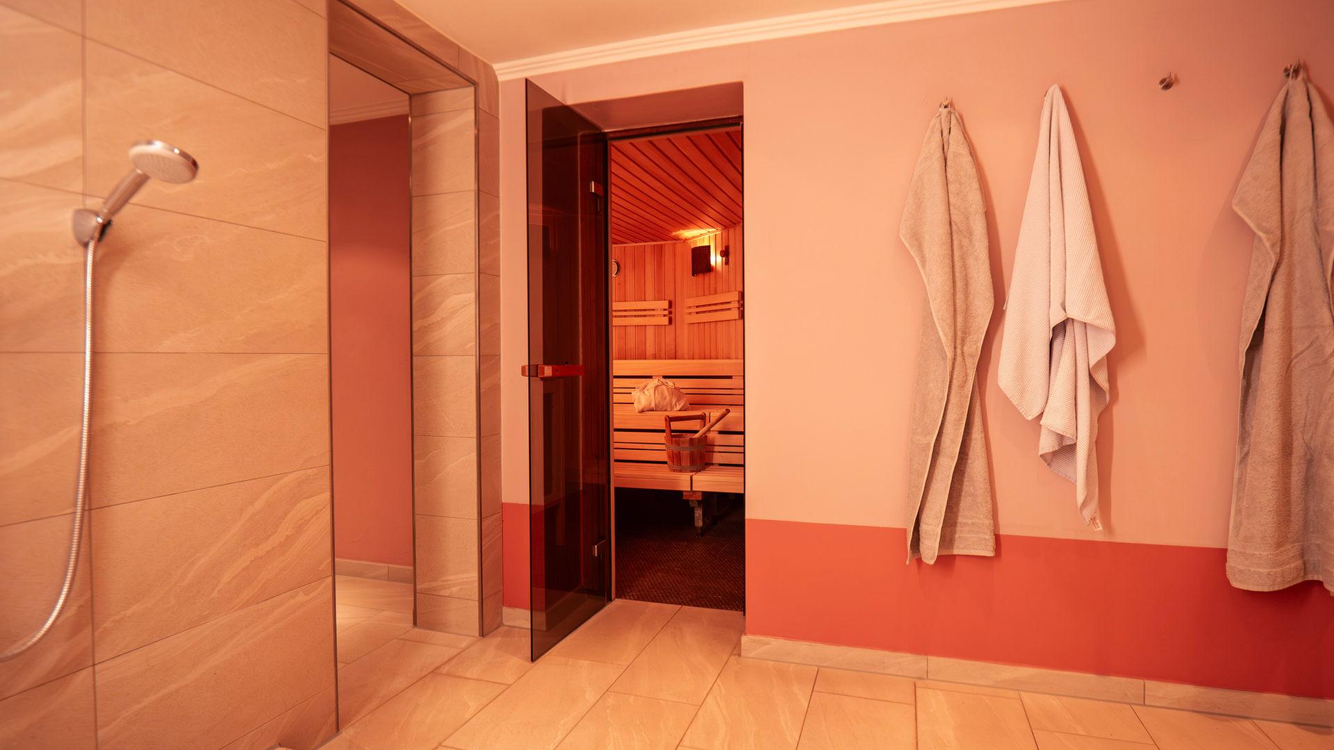 Dusche mit bereitliegenden Handtüchern neben der Saunatür.