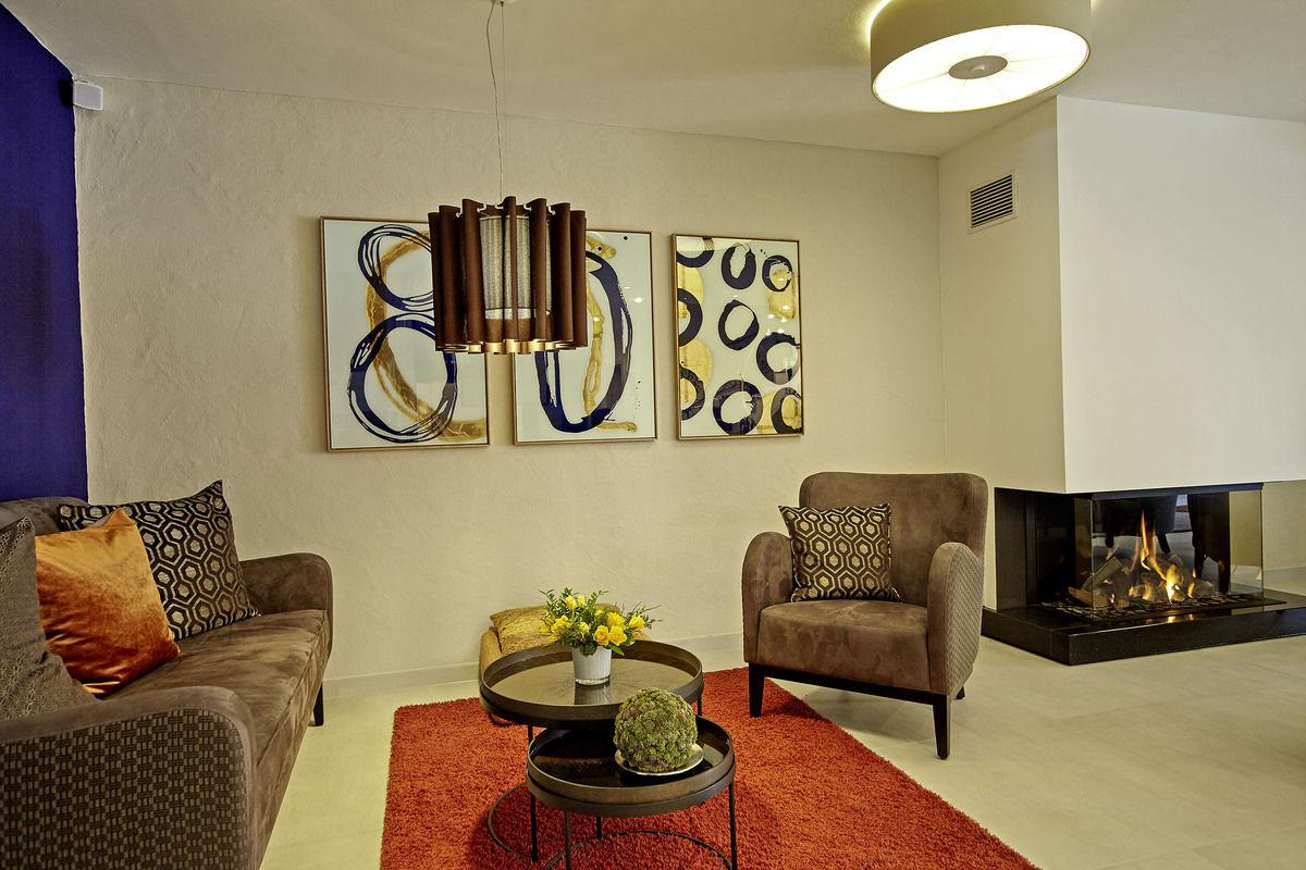 Lounge mit Kamin, Sesseln und abstrakter Kunst an der Wand.