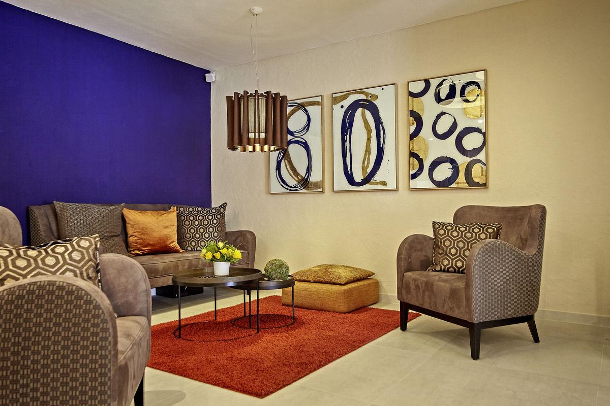 Lounge mit violetter Wand, Sesseln und rotem Teppich.